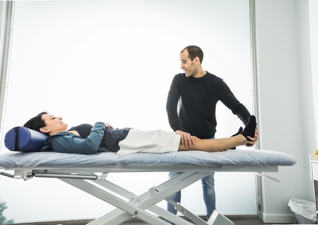 Physiotherapist treating a young woman knee. Concept of physiotherapy, rehabilitation and healingの写真素材