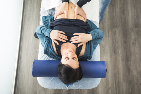 Physiotherapist massaging the belly of a young woman.Physiotherapy and recoveryの写真素材