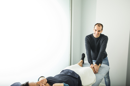 Physiotherapist treating a young woman knee. Concept of physiotherapy, rehabilitation and healingの写真素材