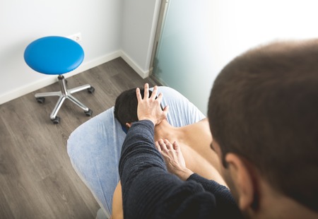 Physiotherapist massaging the back and neck of a young man. Concept of physiotherapyの写真素材