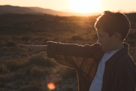 Little boy in the countryside pointing with his finger. Concept of children playing in natureの写真素材