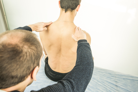Physiotherapist examining a young man back.Physiotherapy concept and physical treatmentの写真素材