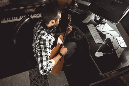 Man playing guitar in a recording studio. Concept guitarist composing songs