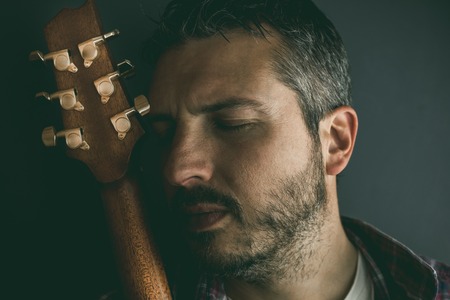 Portrait of a guy with a beard and a guitar. Musician guitarist in studioの写真素材