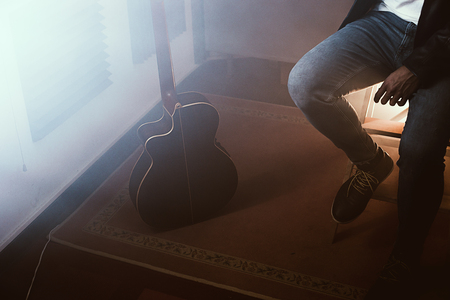 Young man with a classical guitar indoors. Dramatic portrait of a guitaristの写真素材