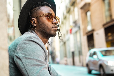 African American man portrait with sunglasses and a modern hat in the street. Concept of black man...