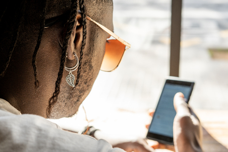 Handsome african american portrait looking at a mobile phone in a coffee shopの写真素材
