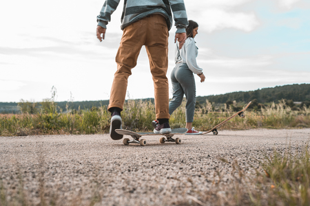 Young couple riding a skateboard on a road. Concept of millenials Skateboarders on skates