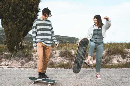 Young couple riding a skateboard on a road. Concept of millenials Skateboarders on skatesの写真素材