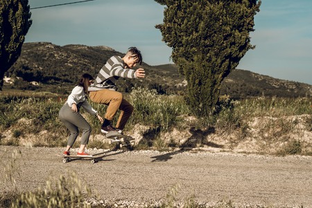 Millennial young couple having fun with a skateboard. Urban sports concept