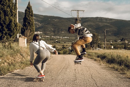 Trendy young couple having fun with a skateboard on the road. Photo style social networksの写真素材