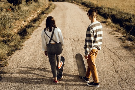 Trendy young couple having fun with a skateboard on the road. Photo style social networksの写真素材