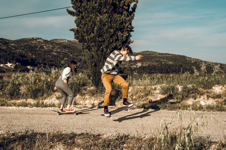 Trendy young couple having fun with a skateboard on the road. Photo style social networksの写真素材