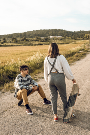 Trendy young couple having fun with a skateboard on the road. Photo style social networksの写真素材