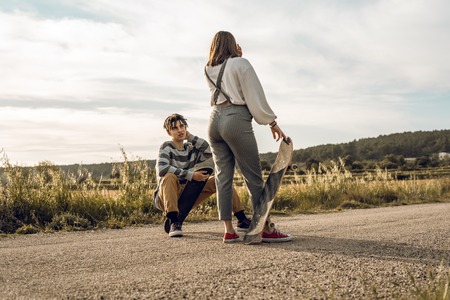 Trendy young couple having fun with a skateboard on the road. Photo style social networksの写真素材