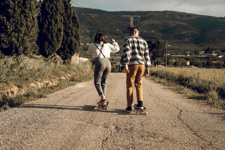 Trendy young couple having fun with a skateboard on the road. Photo style social networksの写真素材