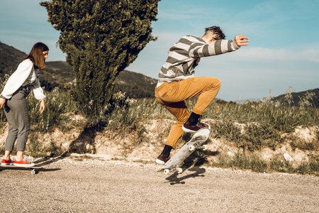 Trendy young couple having fun with a skateboard on the road. Photo style social networksの写真素材