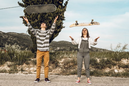 Trendy young couple having fun with a skateboard on the road. Photo style social networksの写真素材