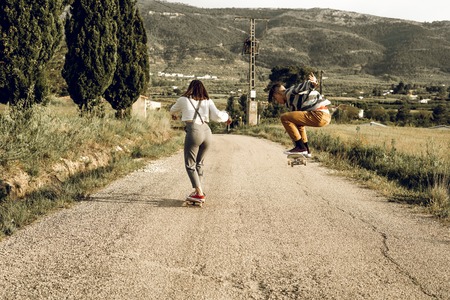 Trendy young couple having fun with a skateboard on the road. Photo style social networksの写真素材