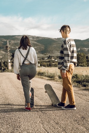 Trendy young couple having fun with a skateboard on the road. Photo style social networksの写真素材