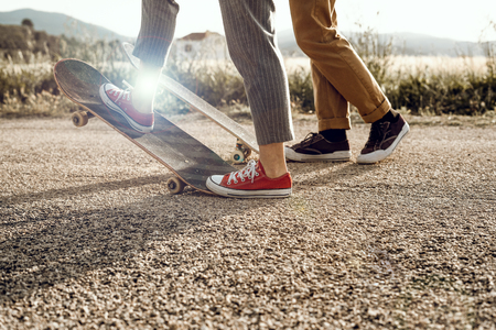 Trendy young couple having fun with a skateboard on the road. Photo style social networksの写真素材