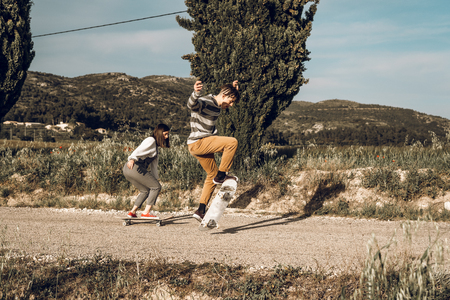 Trendy young couple having fun with a skateboard on the road. Photo style social networksの写真素材