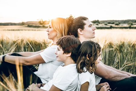 Funny happy family smiling in the field with a sunsetの写真素材