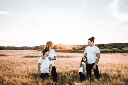 Funny happy family smiling in the field with a sunsetの写真素材