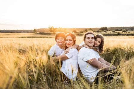 Funny happy family smiling in the field with a sunsetの写真素材