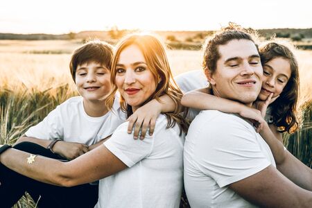 Funny happy family smiling in the field with a sunsetの写真素材