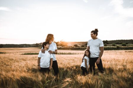 Funny happy family smiling in the field with a sunsetの写真素材