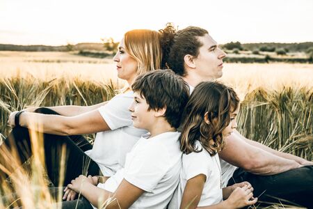 Funny happy family smiling in the field with a sunsetの写真素材