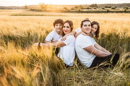 Funny happy family smiling in the field with a sunsetの写真素材