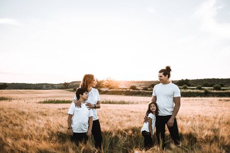 Funny happy family smiling in the field with a sunsetの写真素材