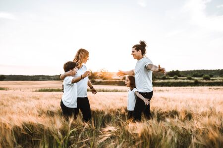 Happy family hugging in the field and smiling at a sunset.の写真素材