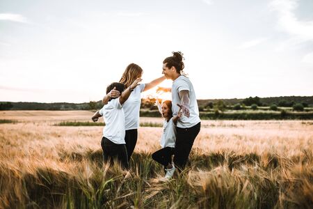 Happy family hugging in the field and smiling at a sunset.の写真素材