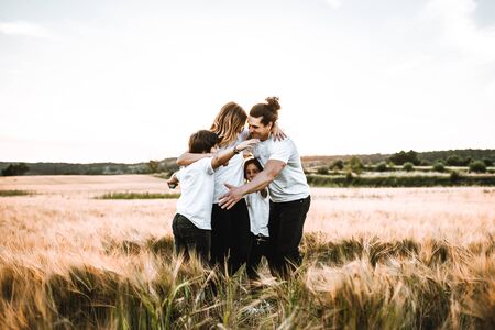 Happy family hugging in the field and smiling at a sunset.の写真素材