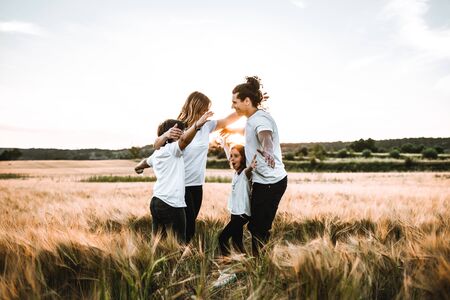 Happy family hugging in the field and smiling at a sunset.の写真素材