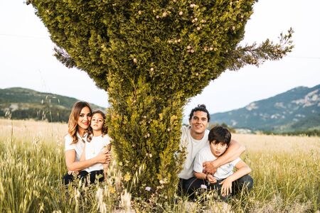 Portrait of a young family smiling and happy looking at the camera on the outside. Family having fun in the countrysideの写真素材