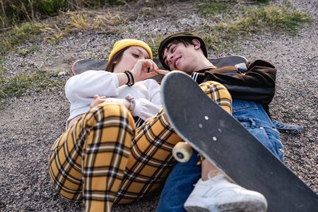 Fashion Lifestyle, Happy casual young couple with skateboard, backlit at sunsetの写真素材