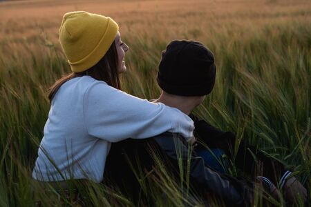 Happy young couple dressed casual in a sunset. Girl and guy kissing in loveの写真素材