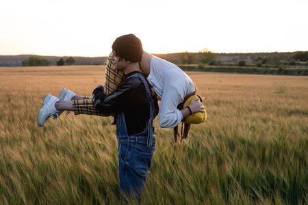 Happy young couple dressed casual in a sunset. Girl and guy kissing in loveの写真素材