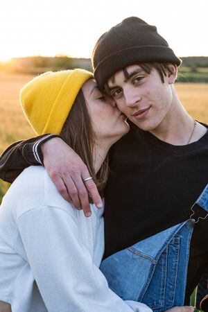 Happy young couple dressed casual in a sunset. Girl and guy kissing in loveの写真素材