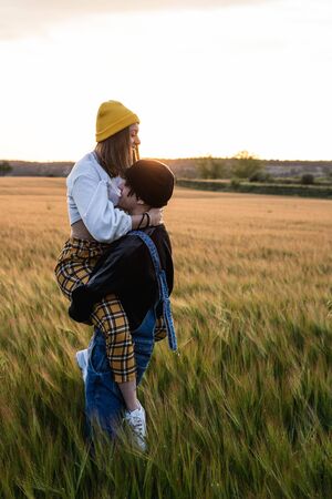 Happy young couple dressed casual in a sunset. Girl and guy kissing in loveの写真素材
