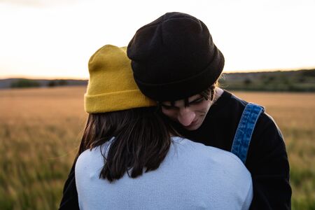 Happy young couple dressed casual in a sunset. Girl and guy kissing in loveの写真素材