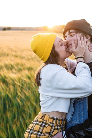 Happy young couple dressed casual in a sunset. Girl and guy kissing in loveの写真素材