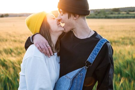 Happy young couple dressed casual in a sunset. Girl and guy kissing in loveの写真素材
