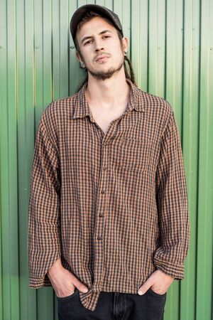Portrait of a modern guy vintage casual dress with cap in the street. Photography style social networks. Young lifestyle conceptの写真素材