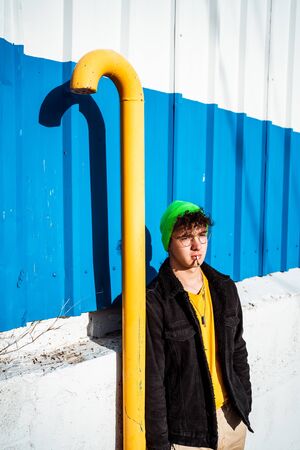 Portrait young guy in the modern city with stylish hat and blue background. Youth Lifestyle Conceptの写真素材