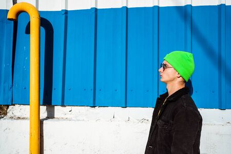 Portrait young guy in the modern city with stylish hat and blue background. Youth Lifestyle Conceptの写真素材